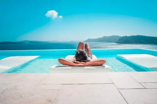 Frau entspannt auf einer Liege am Infinity-Pool über dem Meer