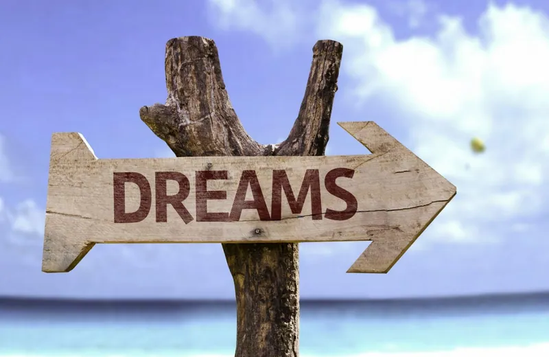 Wegweiser mit der Aufschrift Dreams vor Meer und blauem Himmel